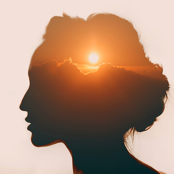 silhouette of a woman with an sunset landscape within her brain